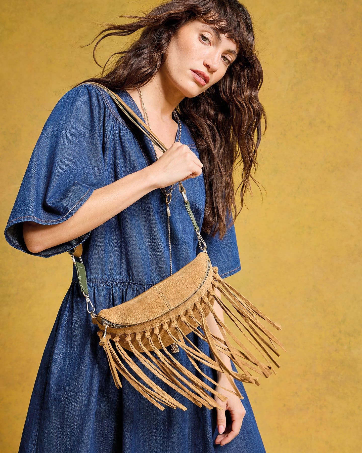 a woman in a blue dress holding a fringe bag