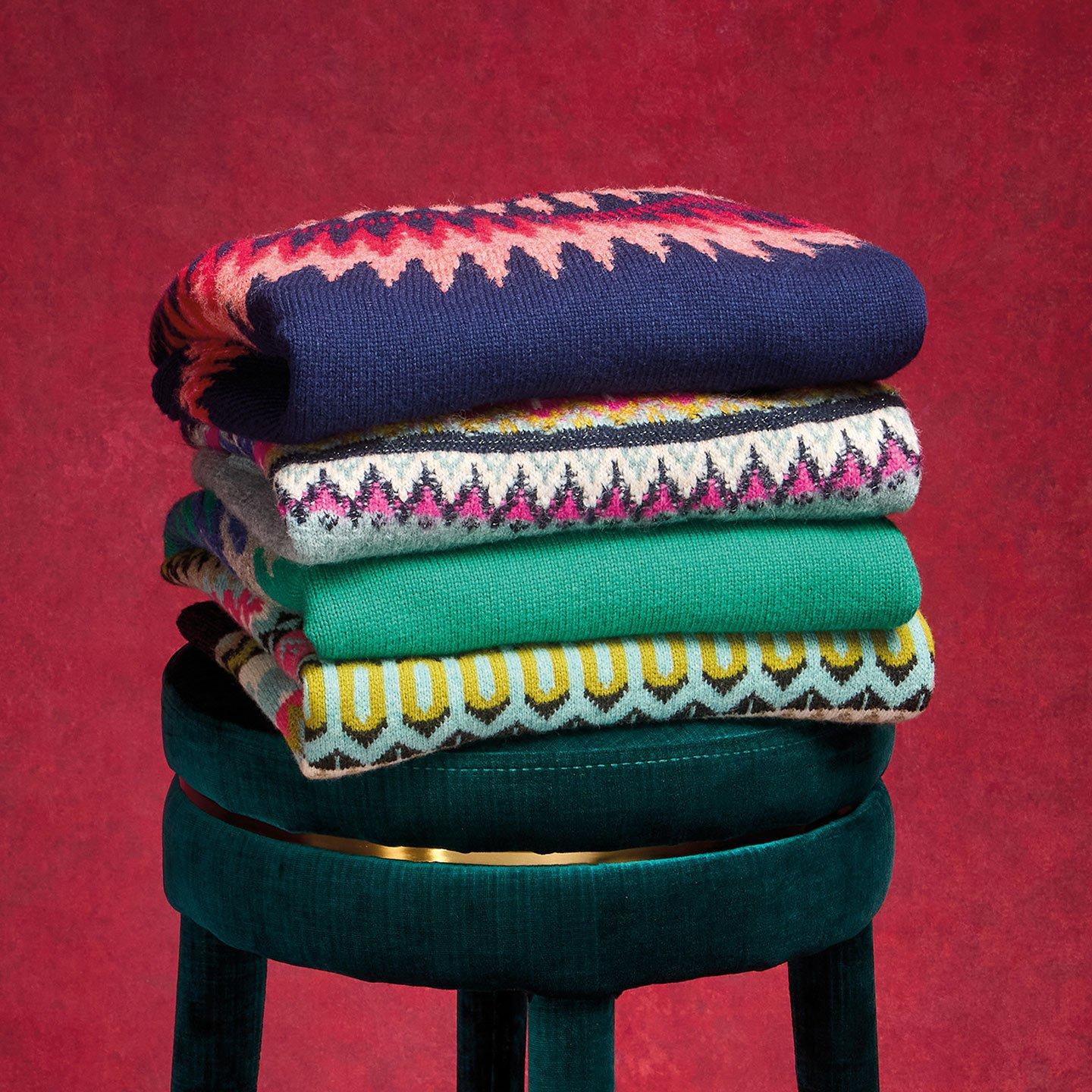 a stack of colorful JUMPERS on a green stool