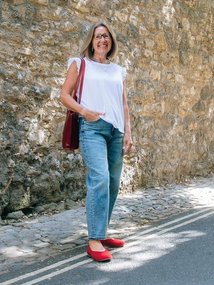 a woman in white White Stuff top standing outside in front of a wall