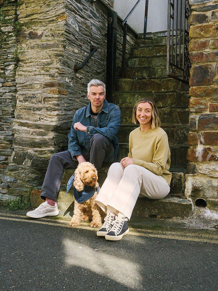 a couple sitting on a stone step with a dog