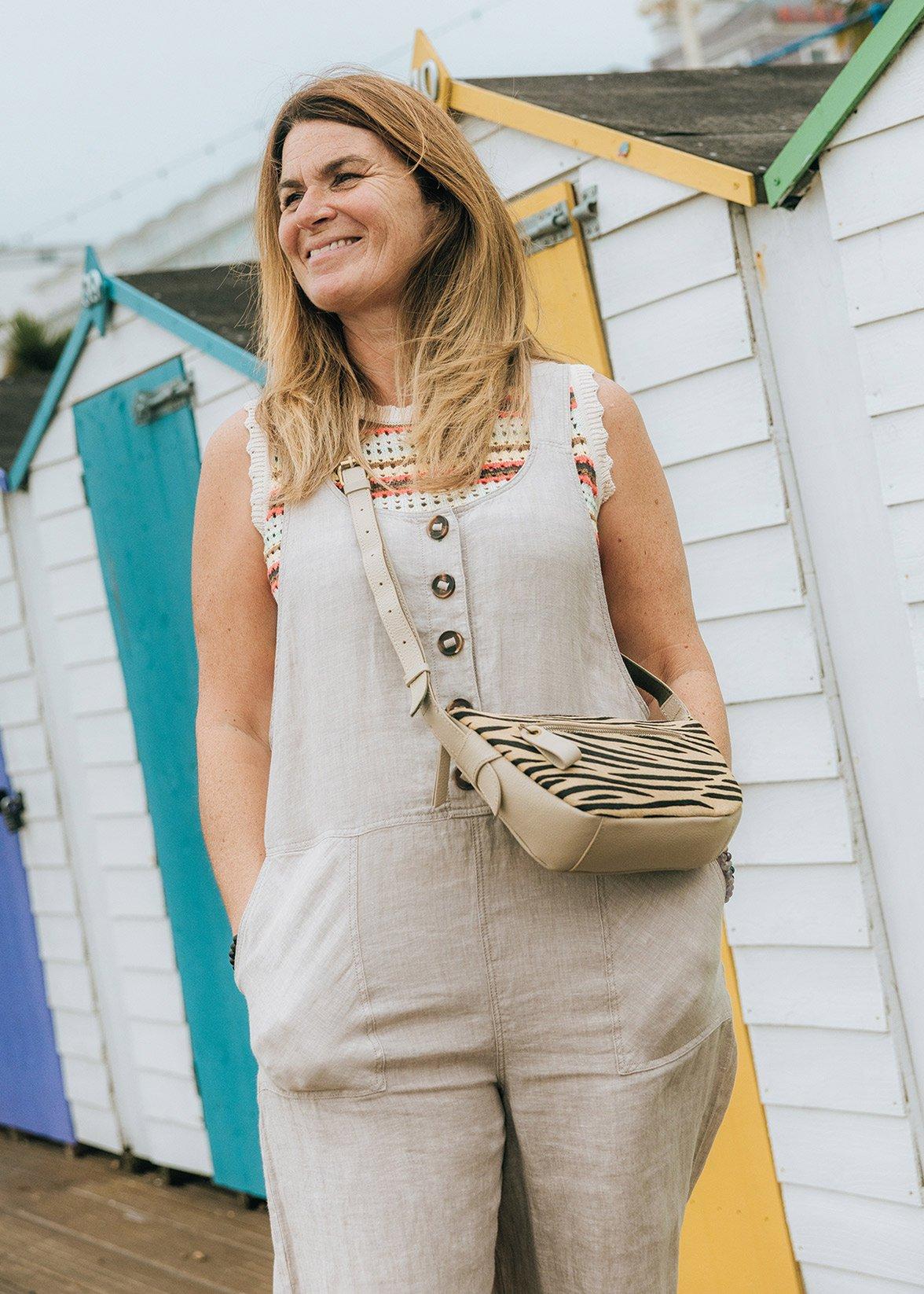a woman standing in front of a row of beach huts wearing White Stuff