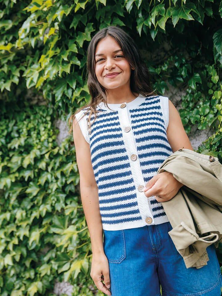 a woman in stripe White Stuff gilet standing outside in front of a hedge