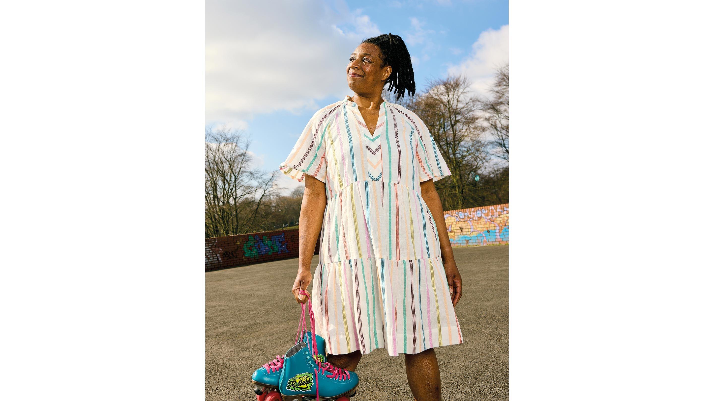 a woman in a dress holding a pink bag and a pair of roller skates