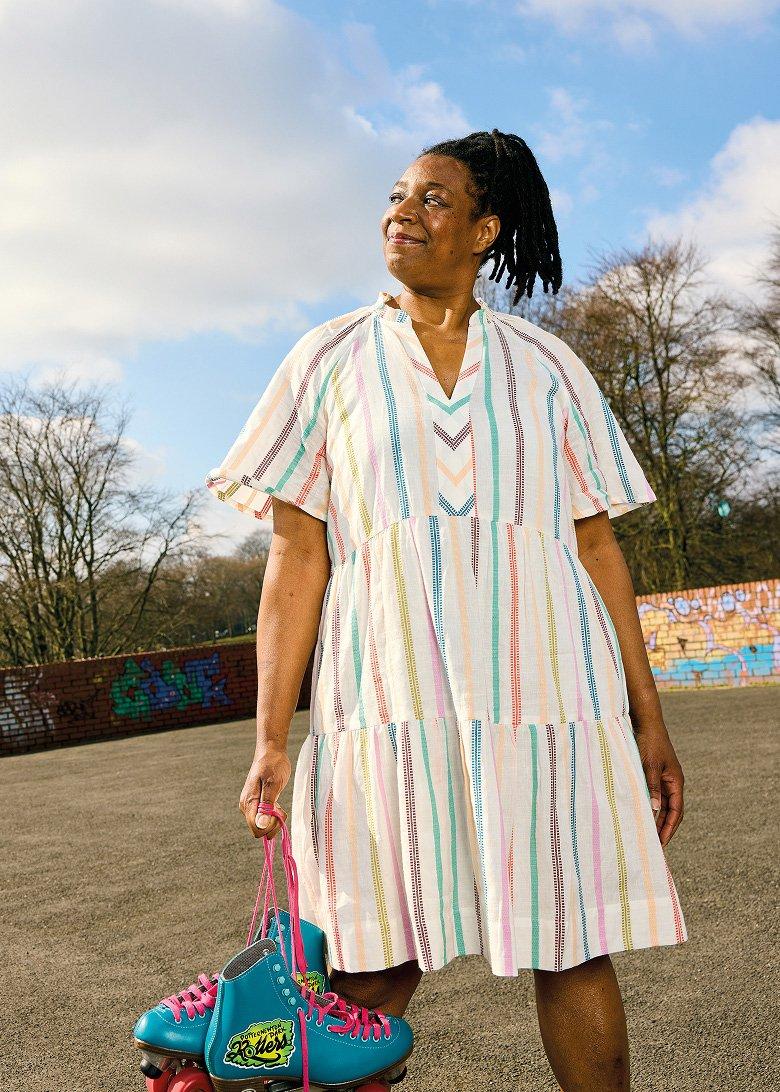 a woman in a dress holding a pair of roller skates