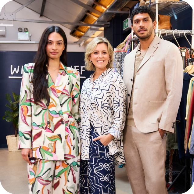 a group of people standing in front of a rack of clothes