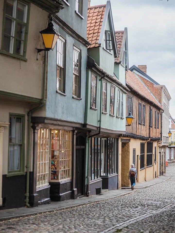 a person walking down a cobblestone street in a small town