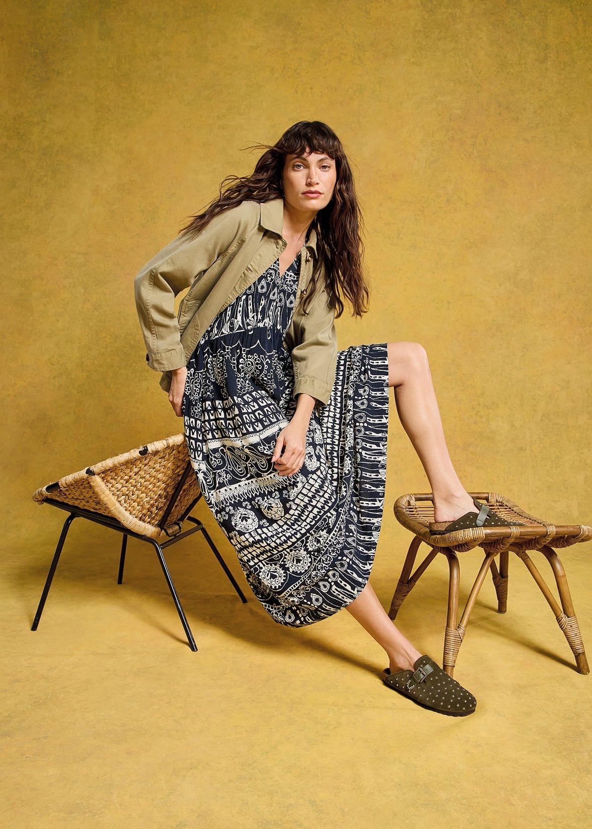 a woman sitting on a chair wearing a dress and jacket