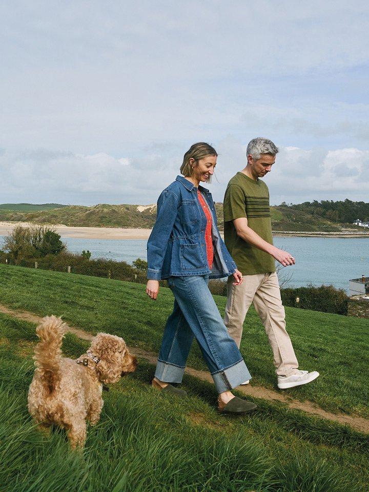 a couple walking a dog by the waterside