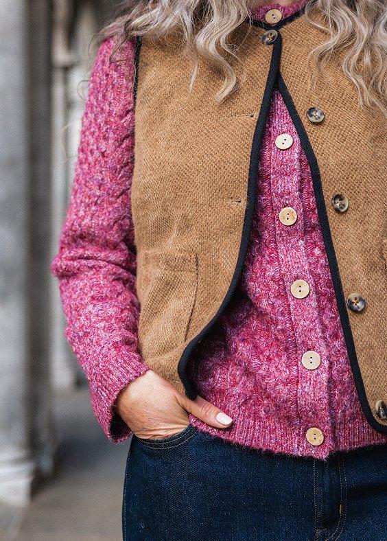 a woman with a pink cardigan and a brown gilet
