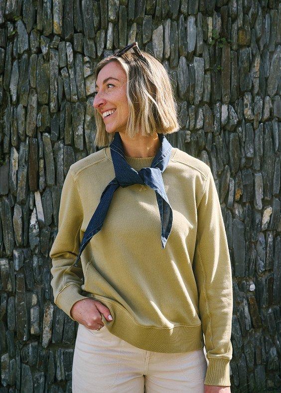 a woman in a sweater standing next to a stone wall
