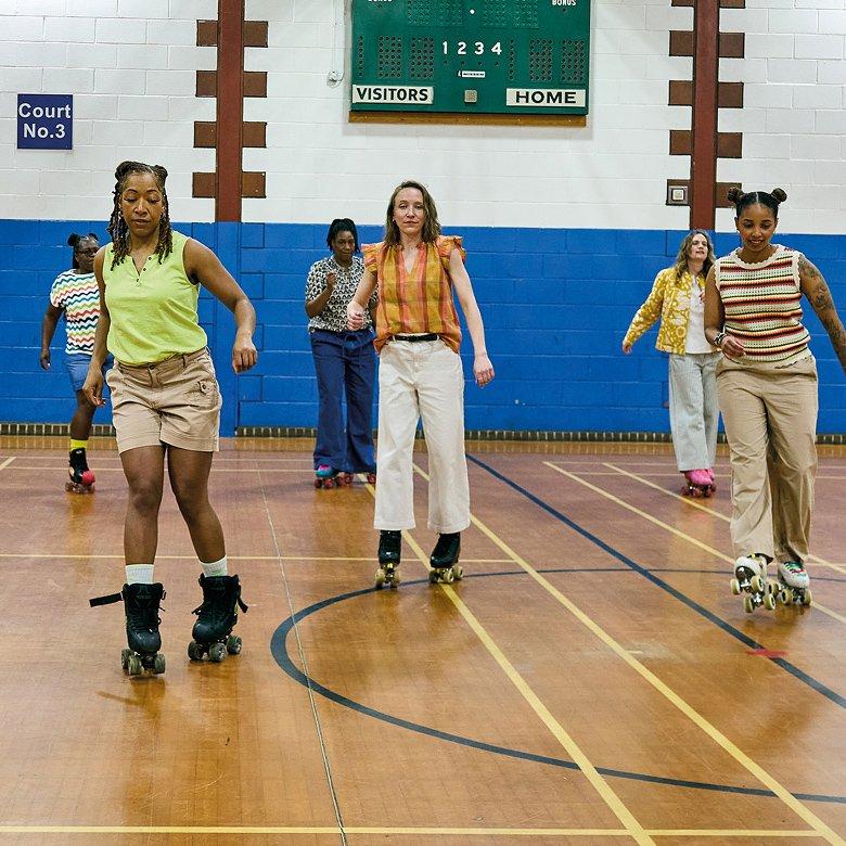 a group of women roller skating on a gymnasium floor