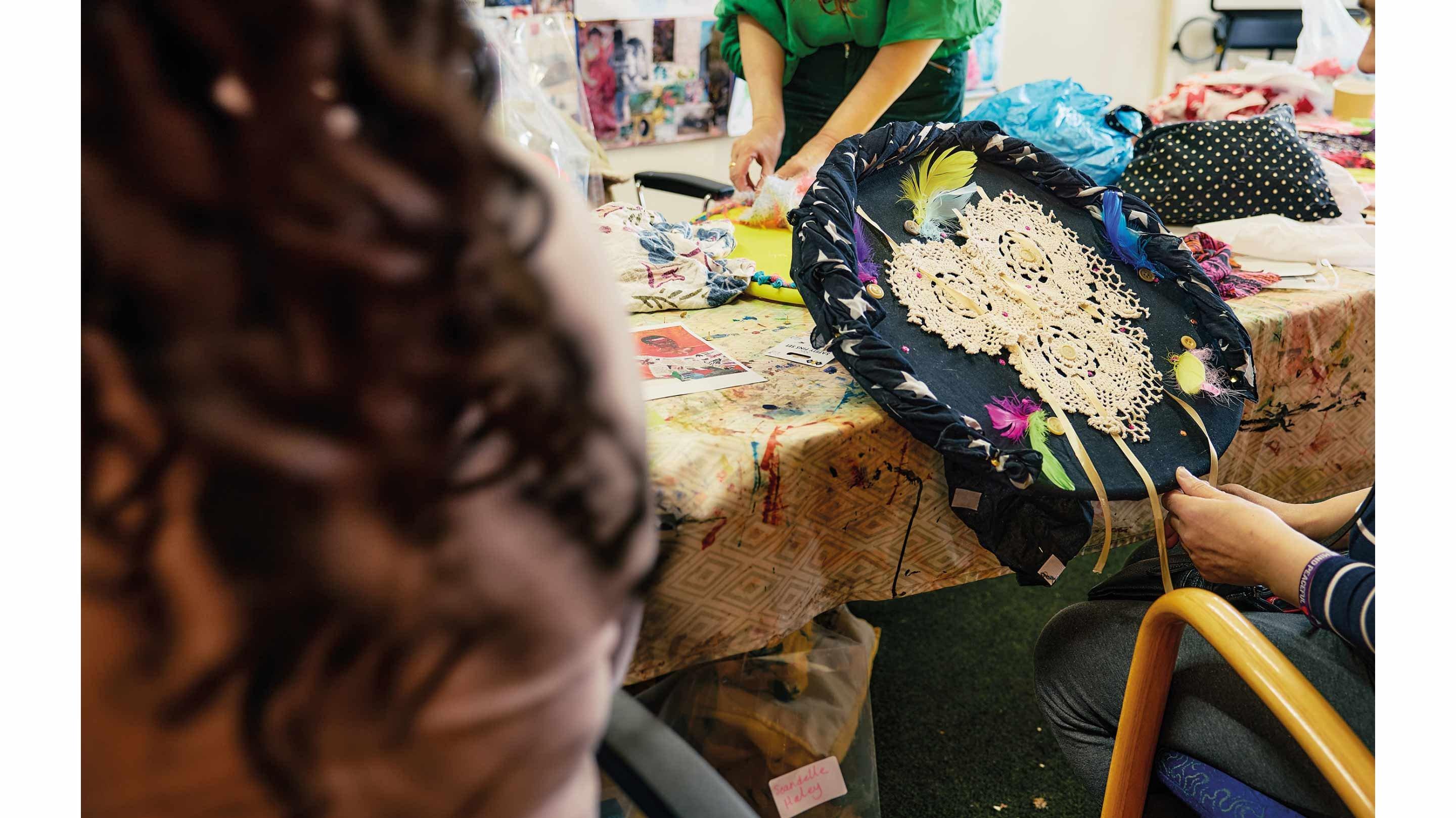 Woman holding fabric circle, sitting at a table.