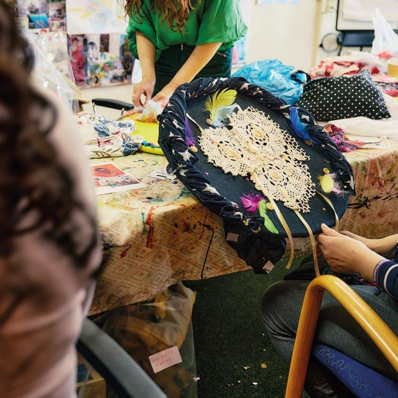 Woman holding fabric circle, sitting at a table.