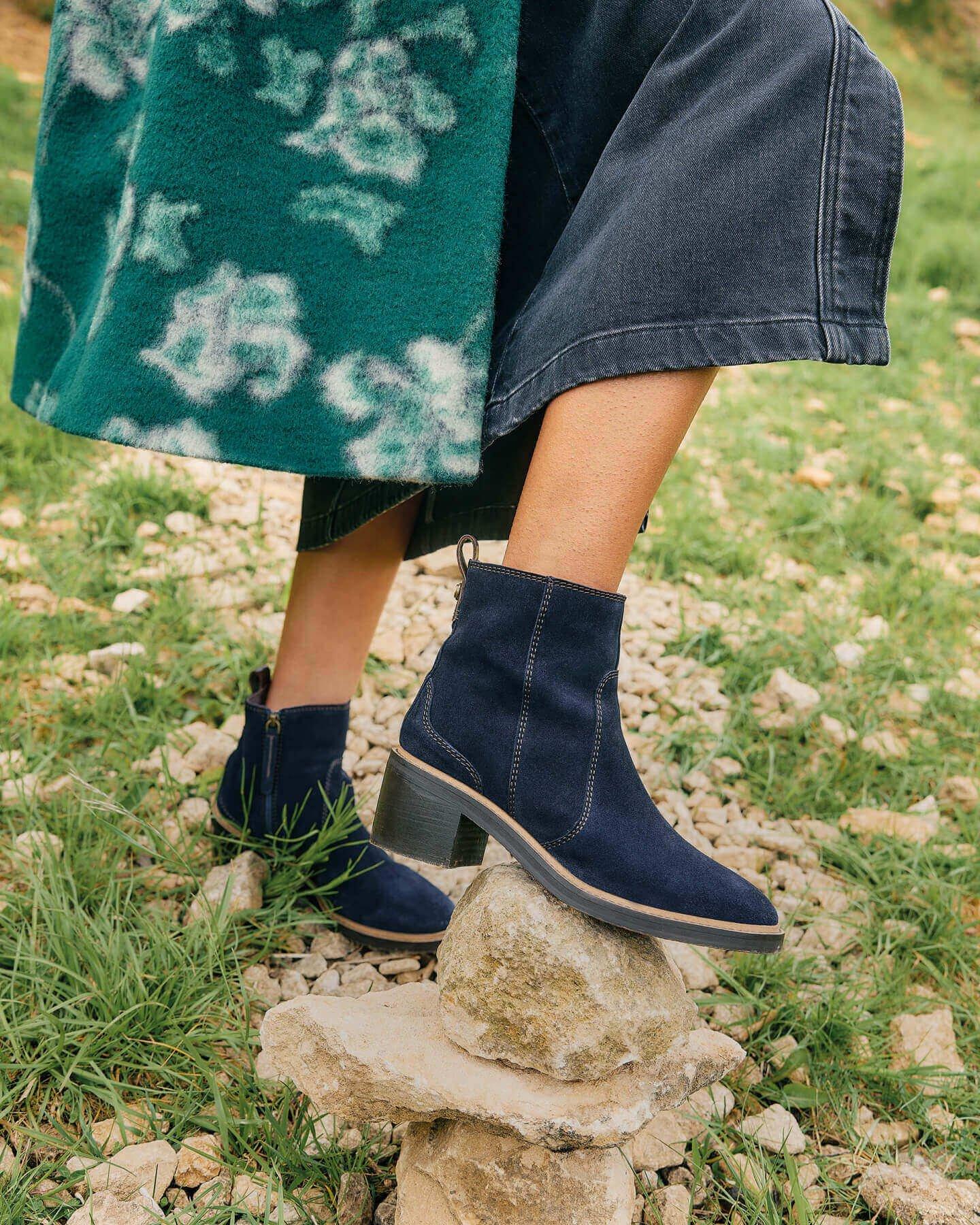 Woman wearing blue suede ankle heeled boots.