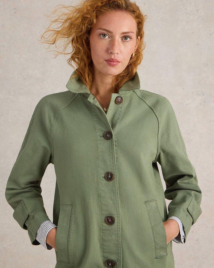 a woman in a green jacket standing with her hands on her hips