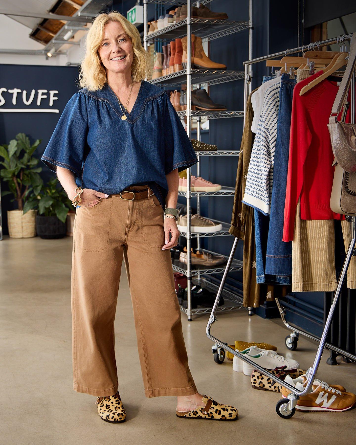 Paula White Stuff's Buying and Design Director standing in front of a rack of clothes with a smile on her face