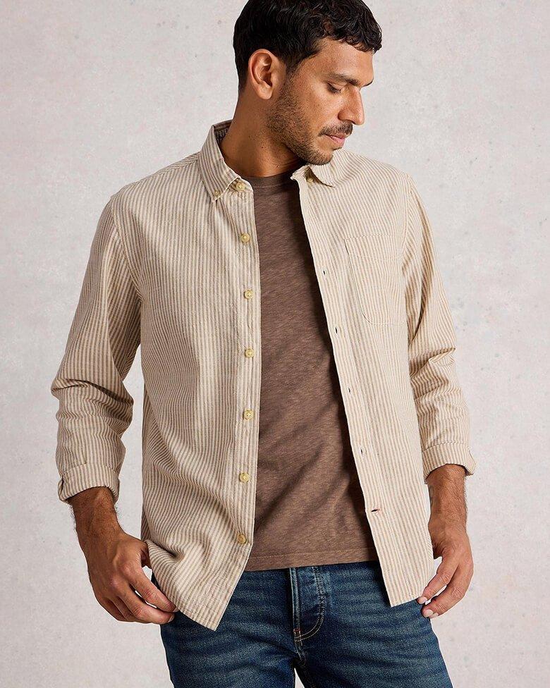a man in a brown t-shirt and striped long sleeve shirt