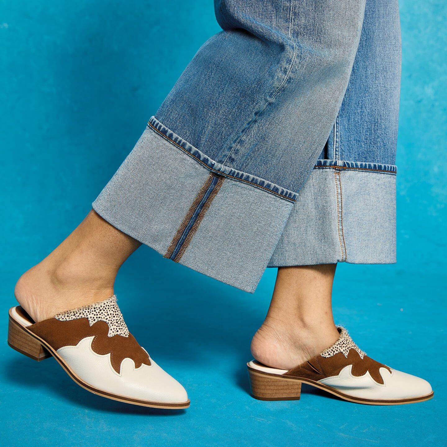 a woman wearing brown and white shoes with a blue background
