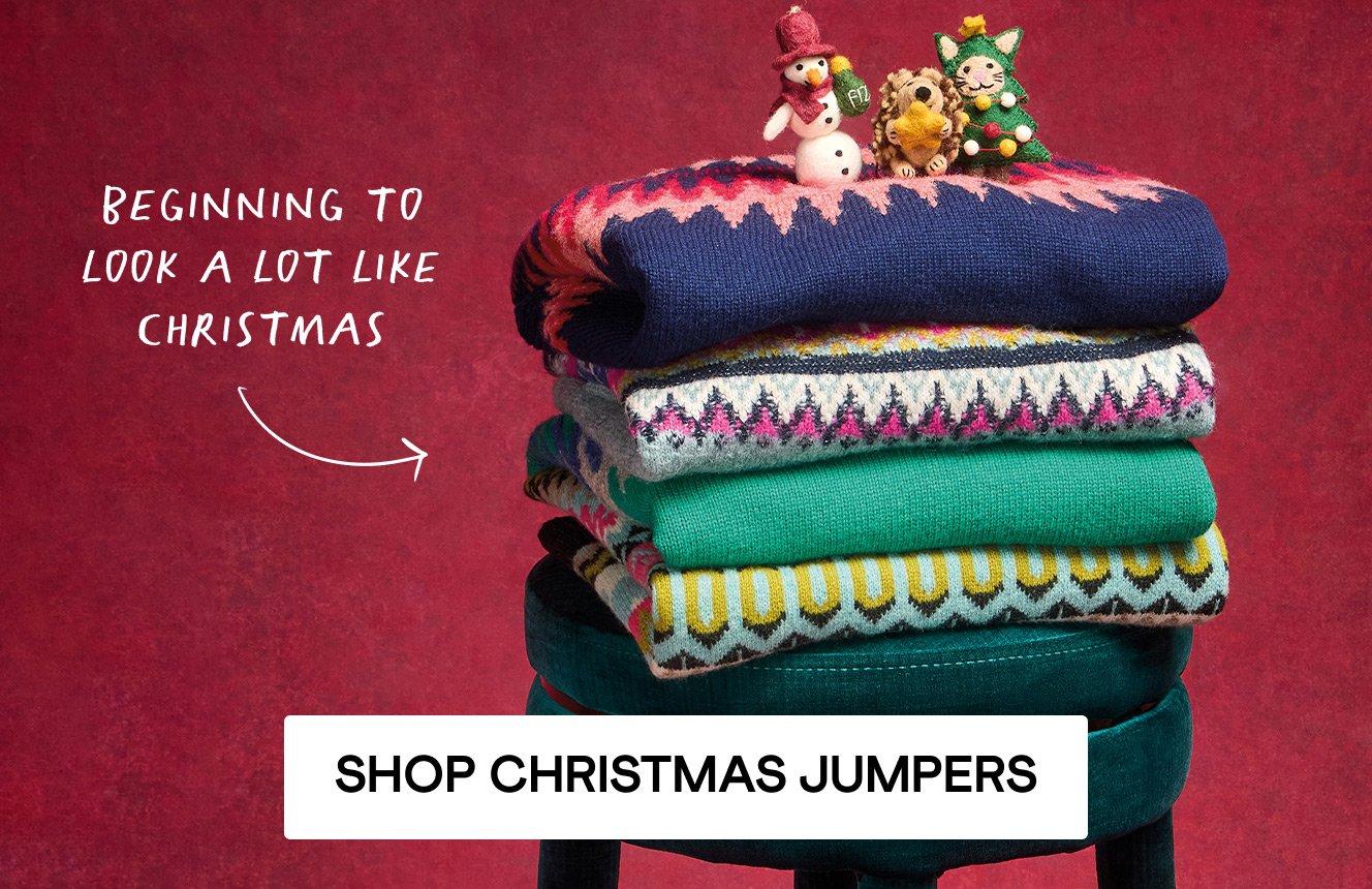 A stack of jumpers, Christmas decorations and gift boxes, Click here to shop Christmas jumpers