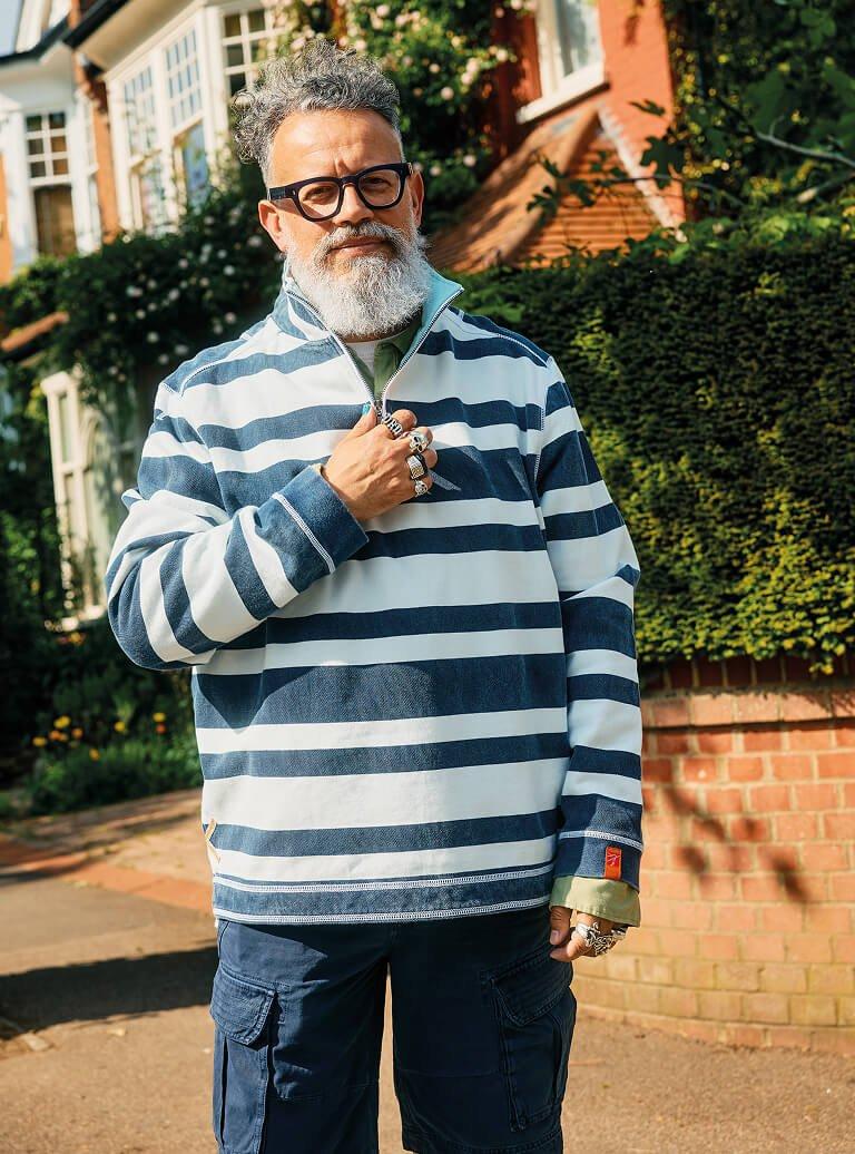a man standing on a street corner wearing a zip up and glasses