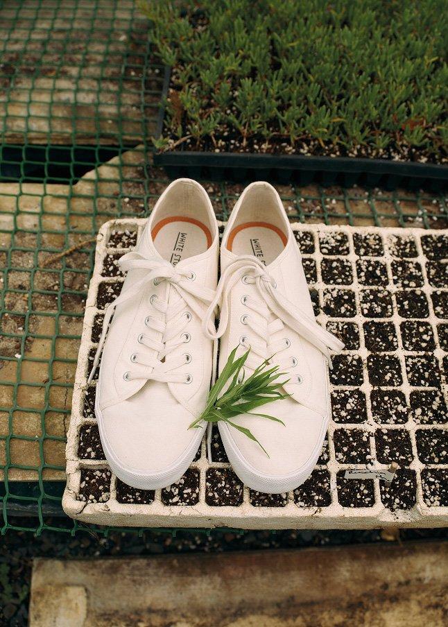 a pair of white shoes sitting on a tray with a plant
