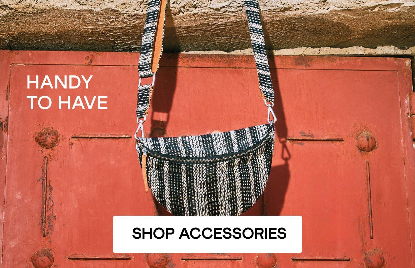A jacquard handbag hanging on a red door with the words 'handy to have' shown on the image. Click here to shop accessories.