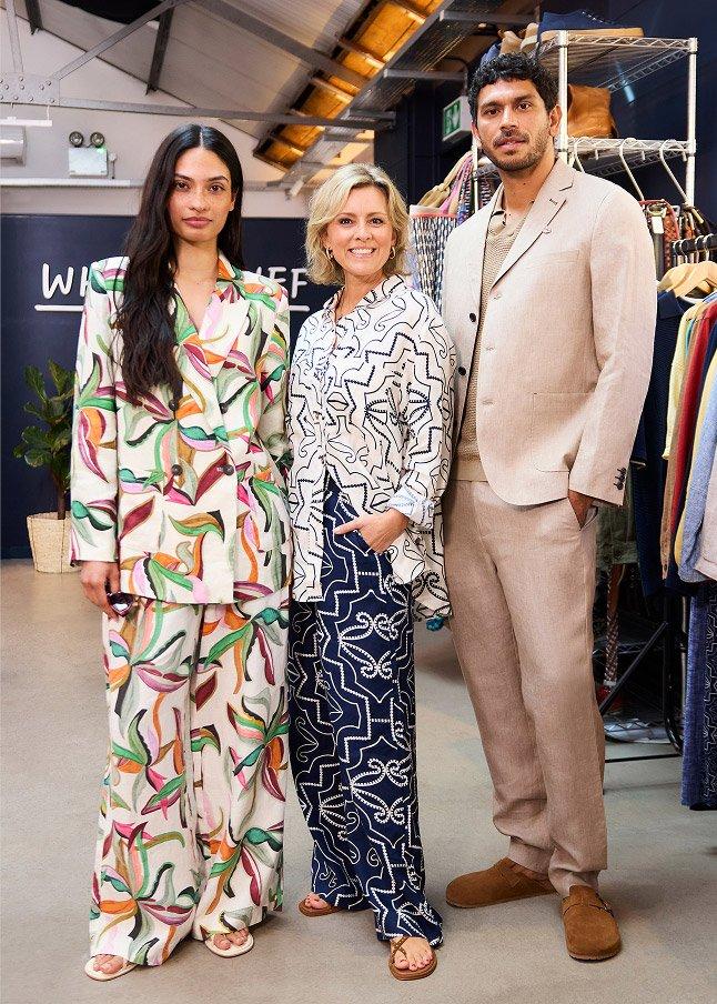 a group of people standing in a store with clothes hanging on racks