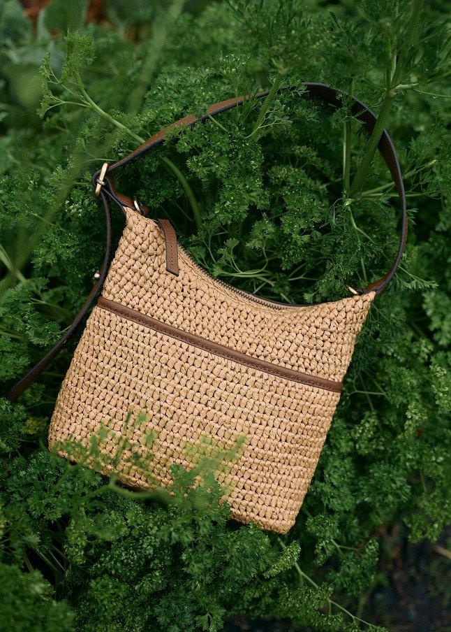 a purse laying on top of a bush of green leaves