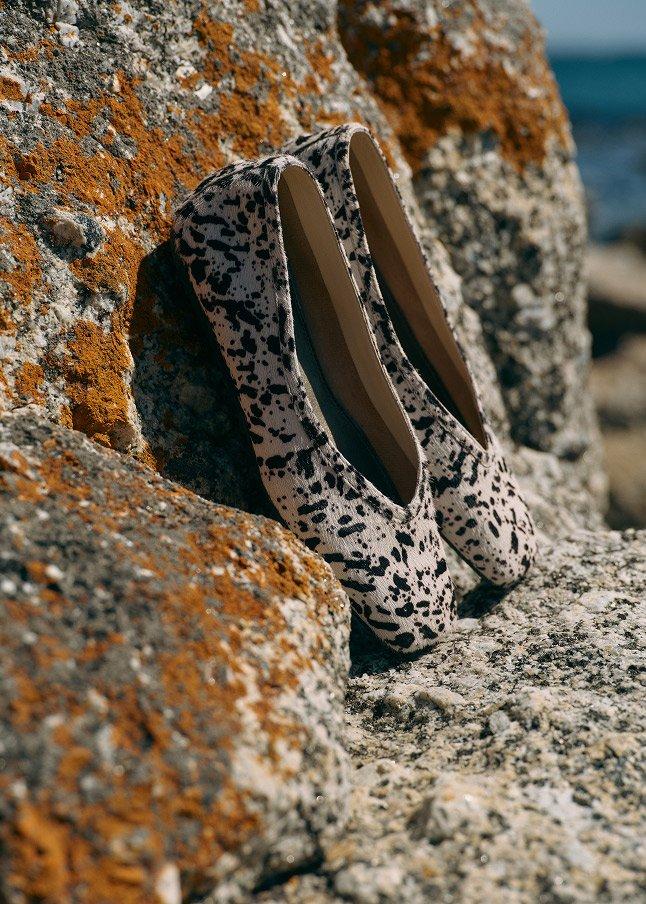 a pair of shoes sitting on top of a rock by the water
