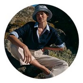 a woman sitting on a rock wearing a hat and shirt