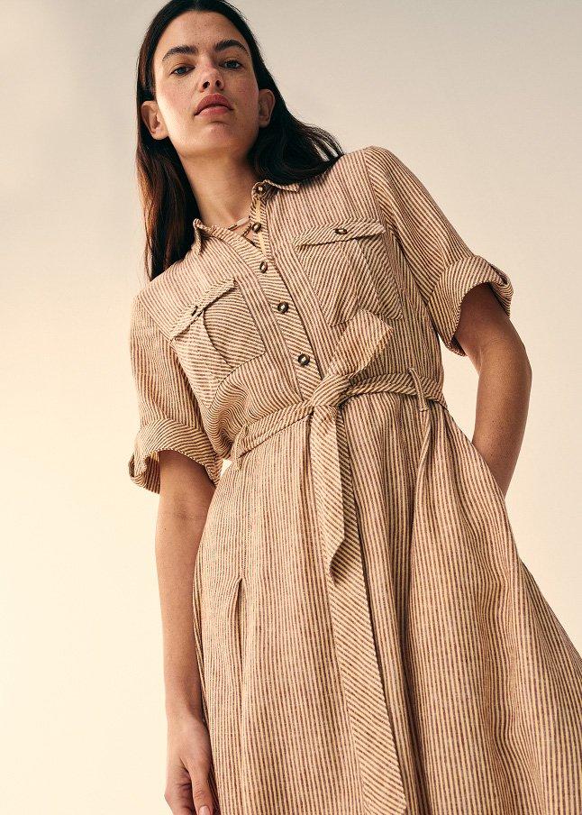 a woman in a striped dress standing up with her hands on her hips