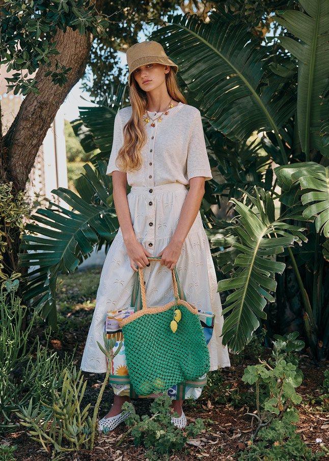 a woman in a white dress holding a green bag