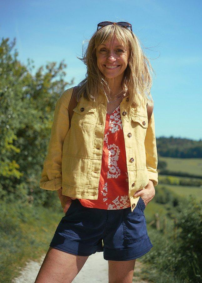 a woman standing on a dirt road with a smile on her face