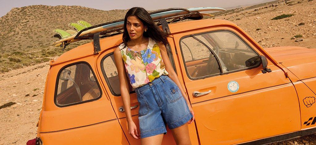 A female model stood again car in the desert wearing White Stuff combat denim shorts and paradise cotton vest. Copy reads 15% off for keyworkers. Click to get your discount.