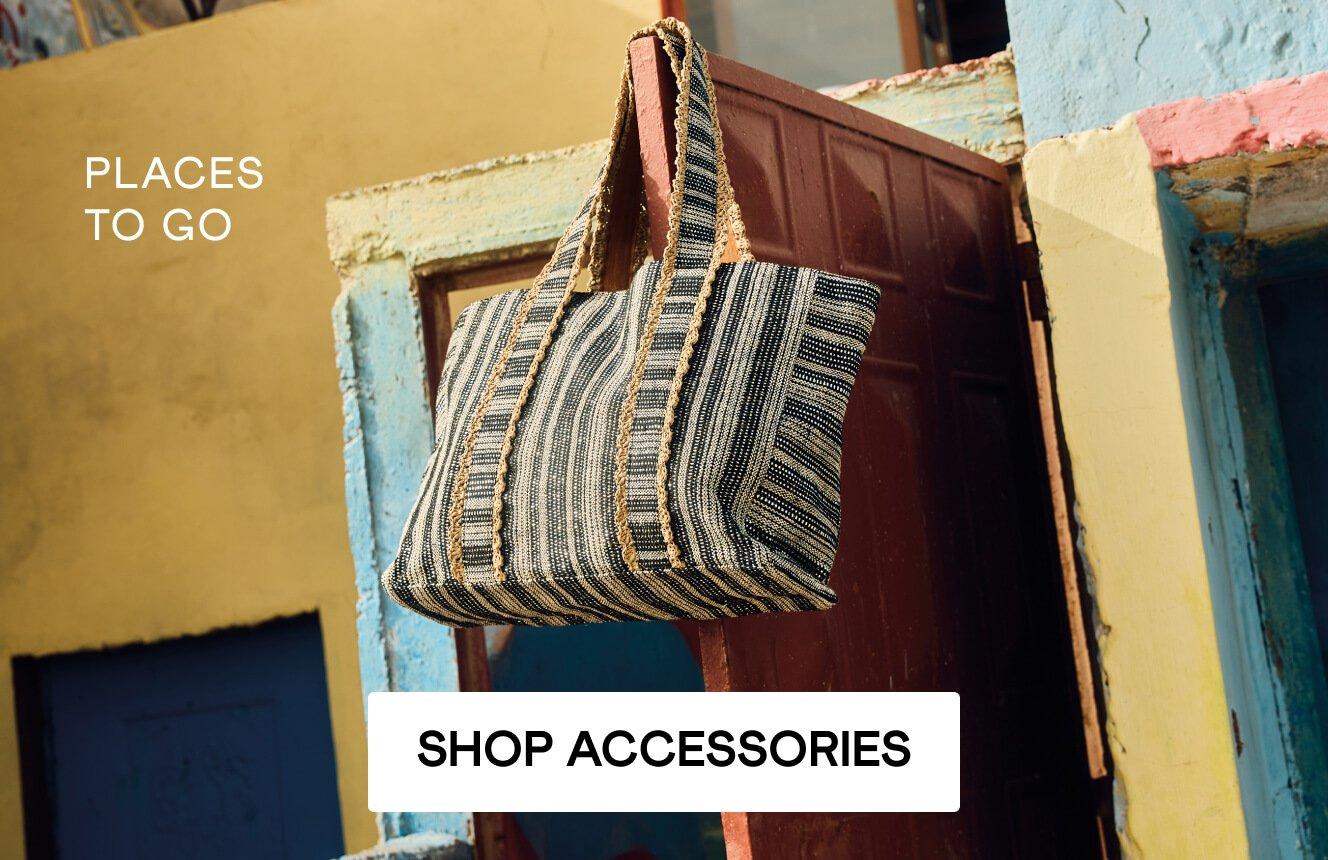 A jacquard tote hanging on a red door with the words 'places to go". Click here to shop accessories.