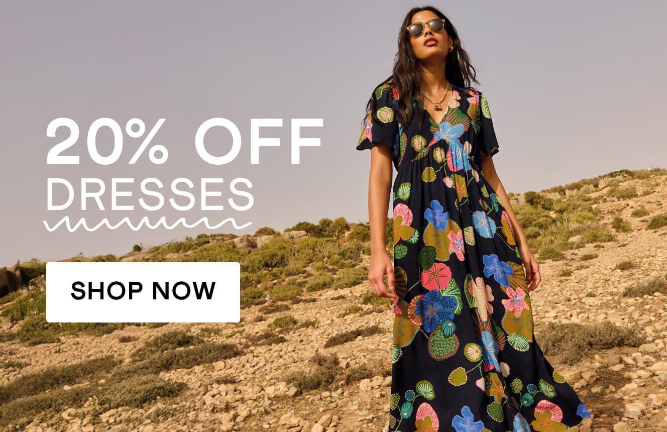 A woman wearing a black dress with geometric patterns in the desert, with the text "20% off dresses", Click here to shop dresses. 