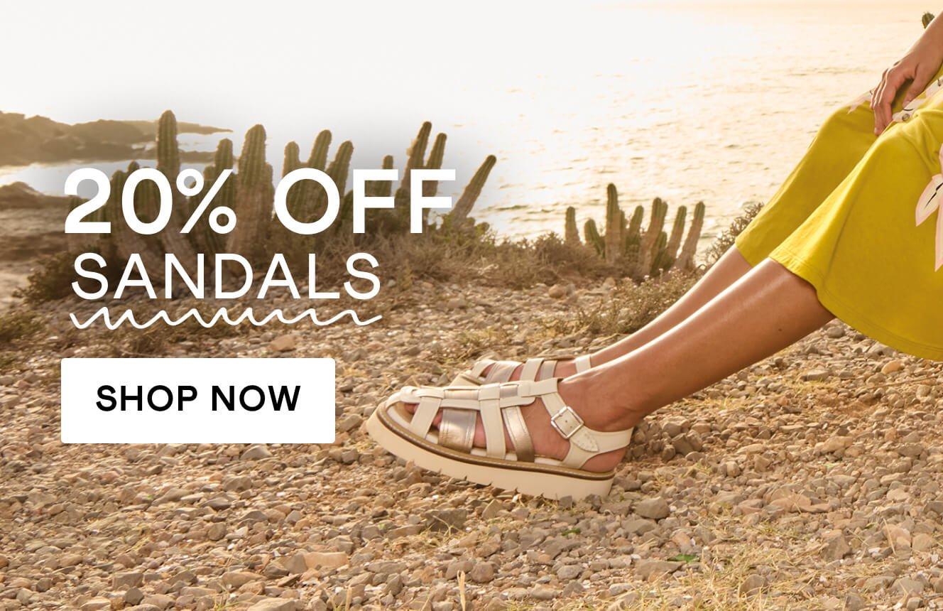 A woman's feet stretched out, wearing white leather fisherman sandals, with the words "20% off sandals". Click here to shop sandals.