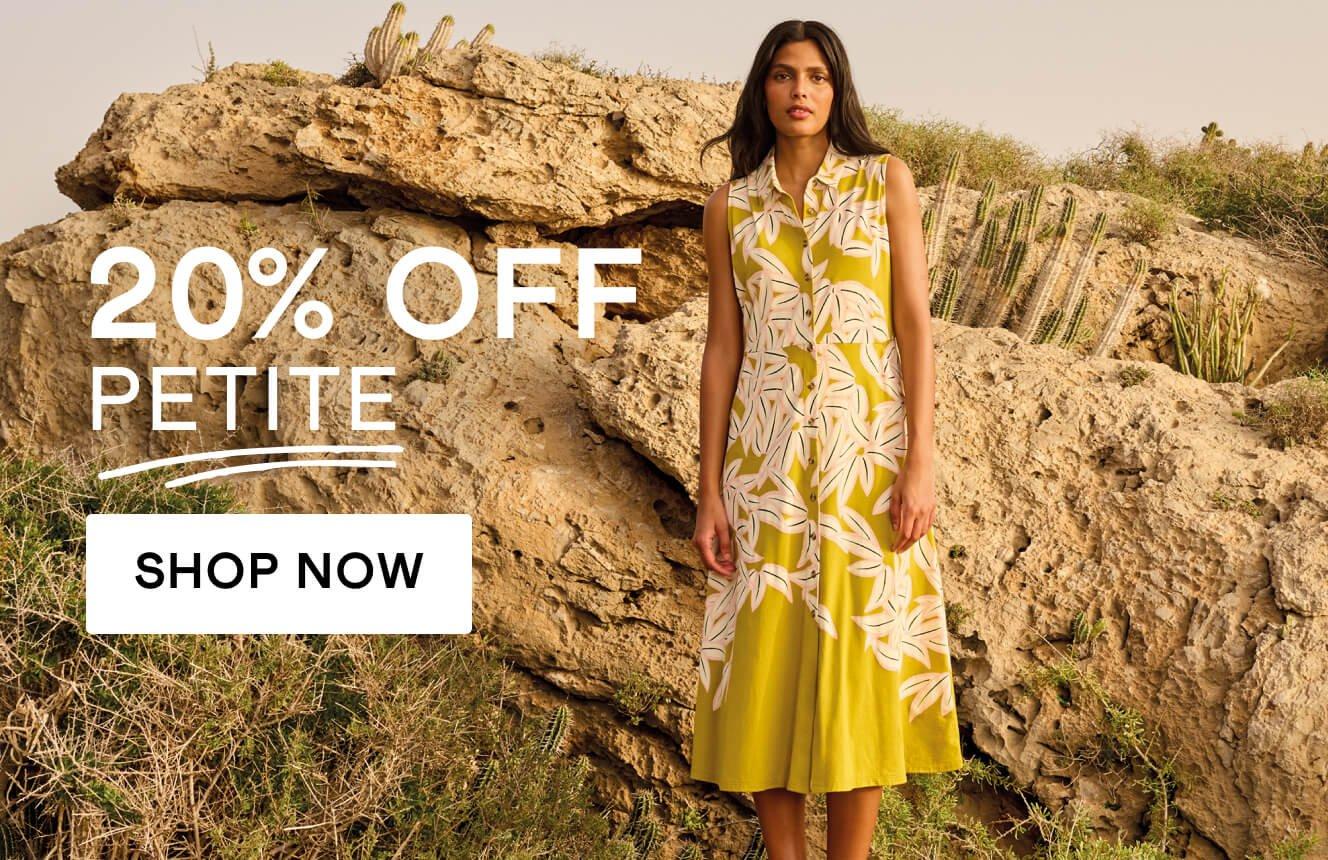 A woman wearing a yellow dress with a floral patters, standing on a box in the desert, with the text "20% off petitein", Click here to shop petite sizes. 