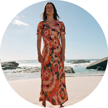 a woman standing on a beach in a long dress