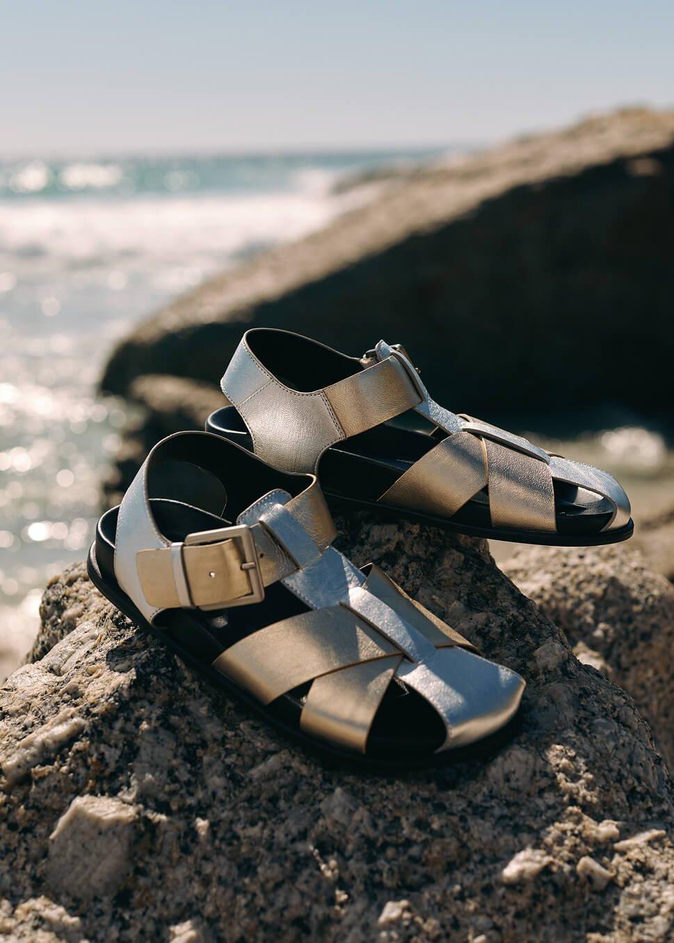 a pair of shoes sitting on a rock by the ocean