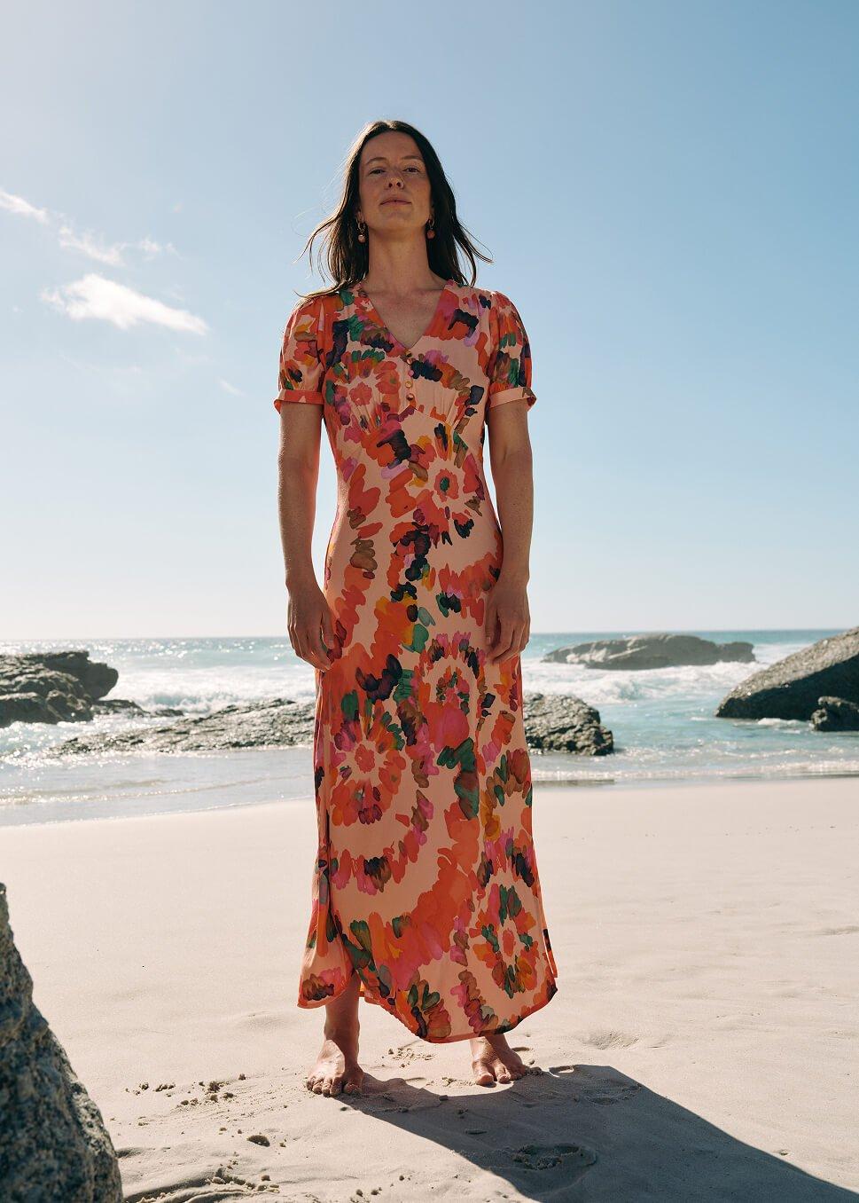 a woman standing on a beach in a long dress