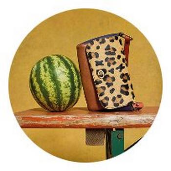 a watermelon and a purse on a table with a yellow background