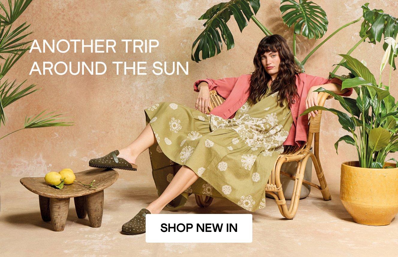 A woman wearing the yellow  Eva Dress and the Red Eden Denim Jacket. Text on the image is "another trip around the sun. Click here to shop new in.