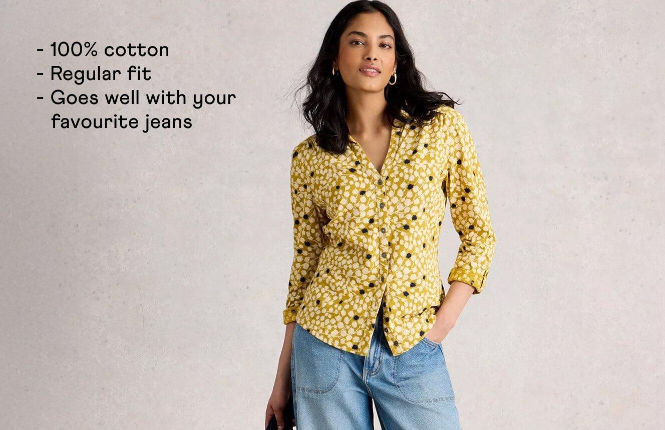 A woman wearing the yellow Annie Shirt with a floral print. Text on the image is "100% cotton, regular fit, goes well with your favourite jeans!".