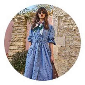 a woman in a blue dress and brown bag standing in a circle