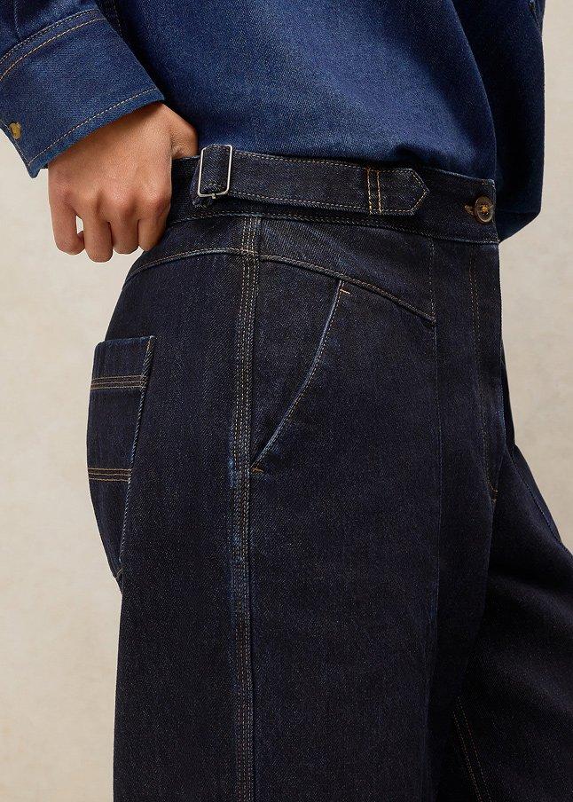a woman in a blue shirt and blue jeans is holding her belt