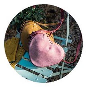 a close up of a purse sitting on a chair next to a flower