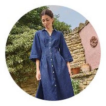 a woman in a denim dress is standing in front of a wall