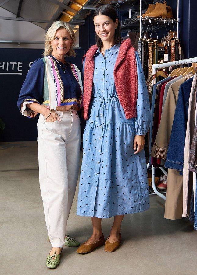 two women standing next to each other in a clothing store