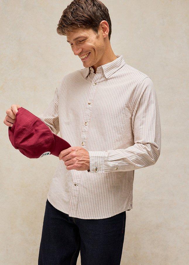 a man in a shirt and tie holding a red hat
